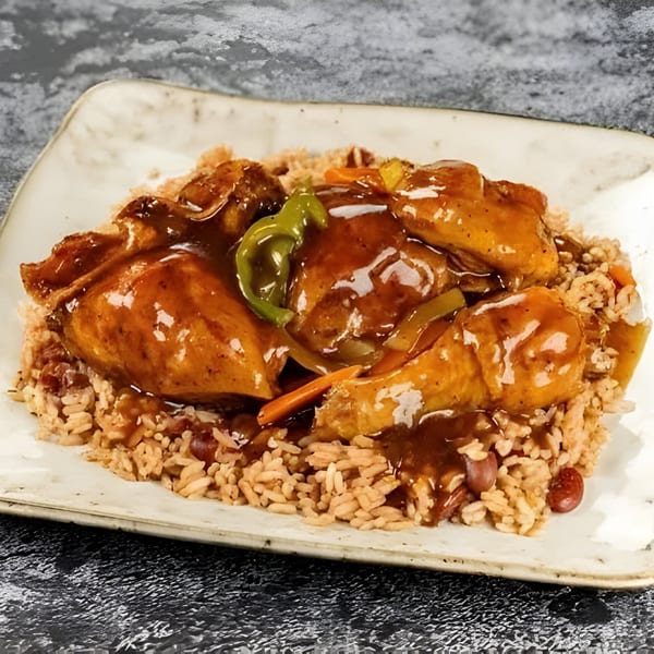 Jerk N Go's brown stew chicken with rice and peas, garnished with green peppers and carrots.