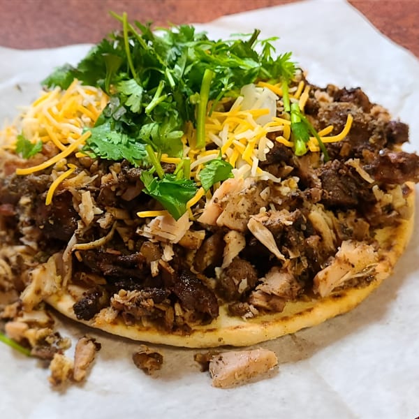 Jerk N Go's Jamaican flatbread topped with shredded jerk chicken, cheese, and fresh cilantro.