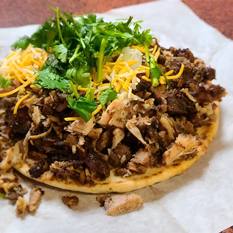Jerk N Go's Jamaican flatbread topped with shredded jerk chicken, cheese, and cilantro.