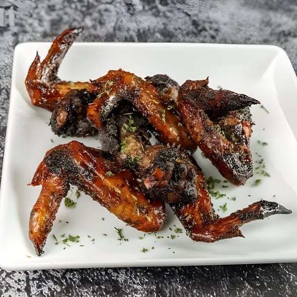 Close-up of Jerk N Go's Jamaican jerk chicken wings, glistening with sauce and sprinkled with herbs.