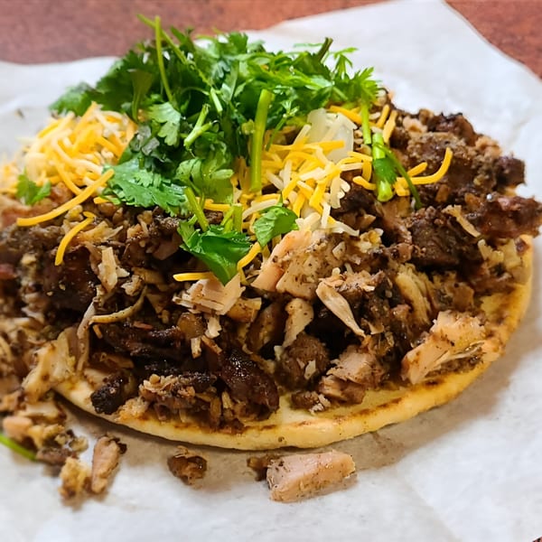 Jerk N Go's Jamaican flatbread topped with jerk chicken, cheese, and cilantro.