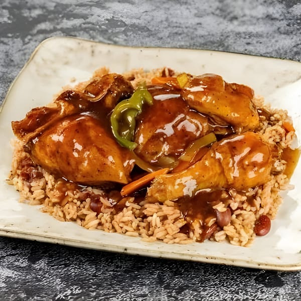 Jerk N Go's brown stew chicken with rice and peas, garnished with peppers and carrots.
